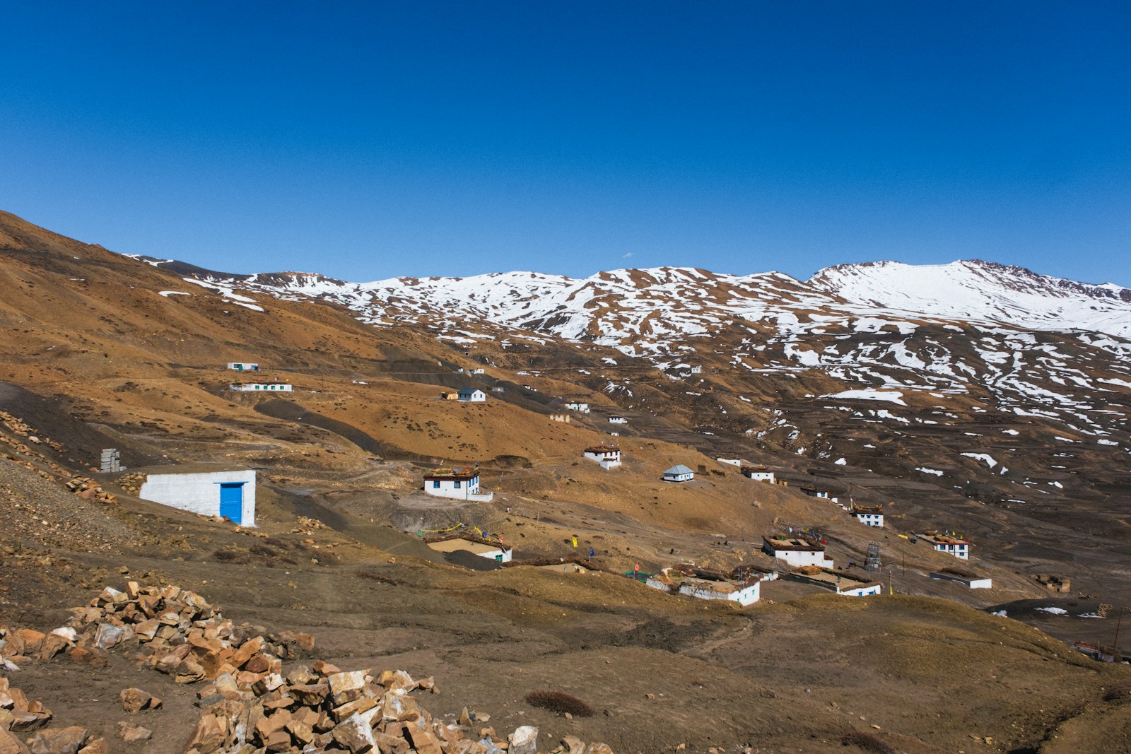 Whitewashed homes beneath bare mountains and a blue sky in Spiti.