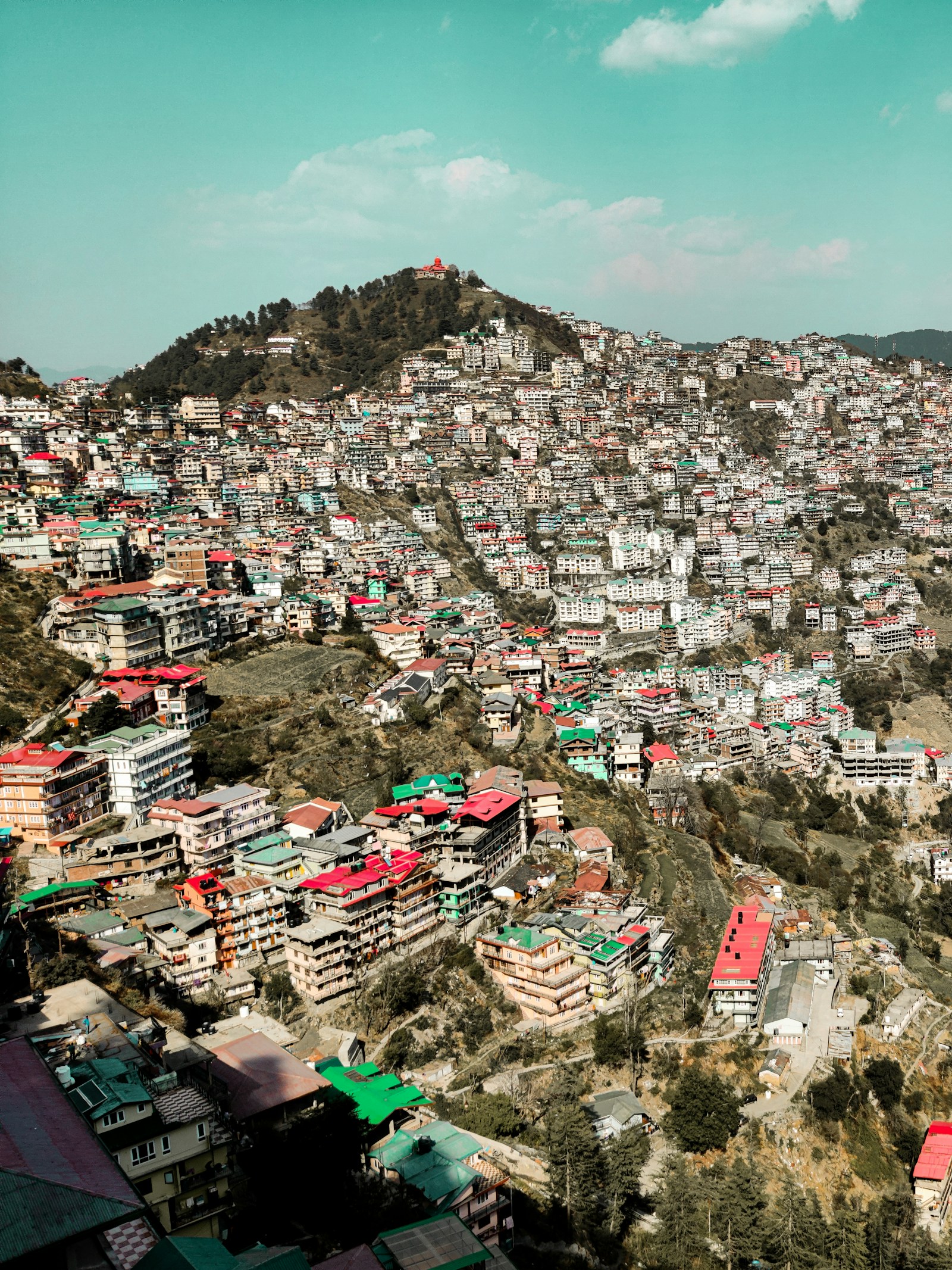 Hillside buildings in Sanjauli, Shimla, beneath a partly cloudy sky.